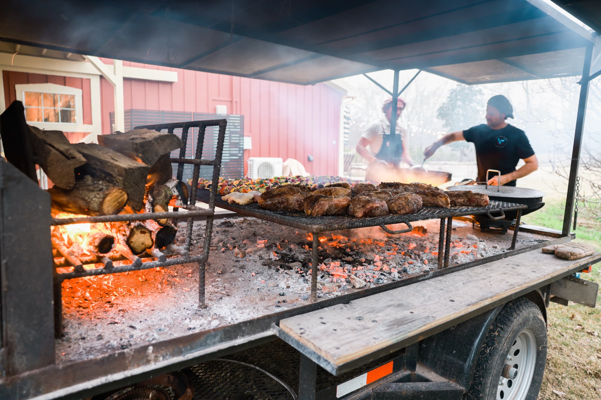 Prime cuts of beef grilling over an open wood fire at a St Lumaz asado