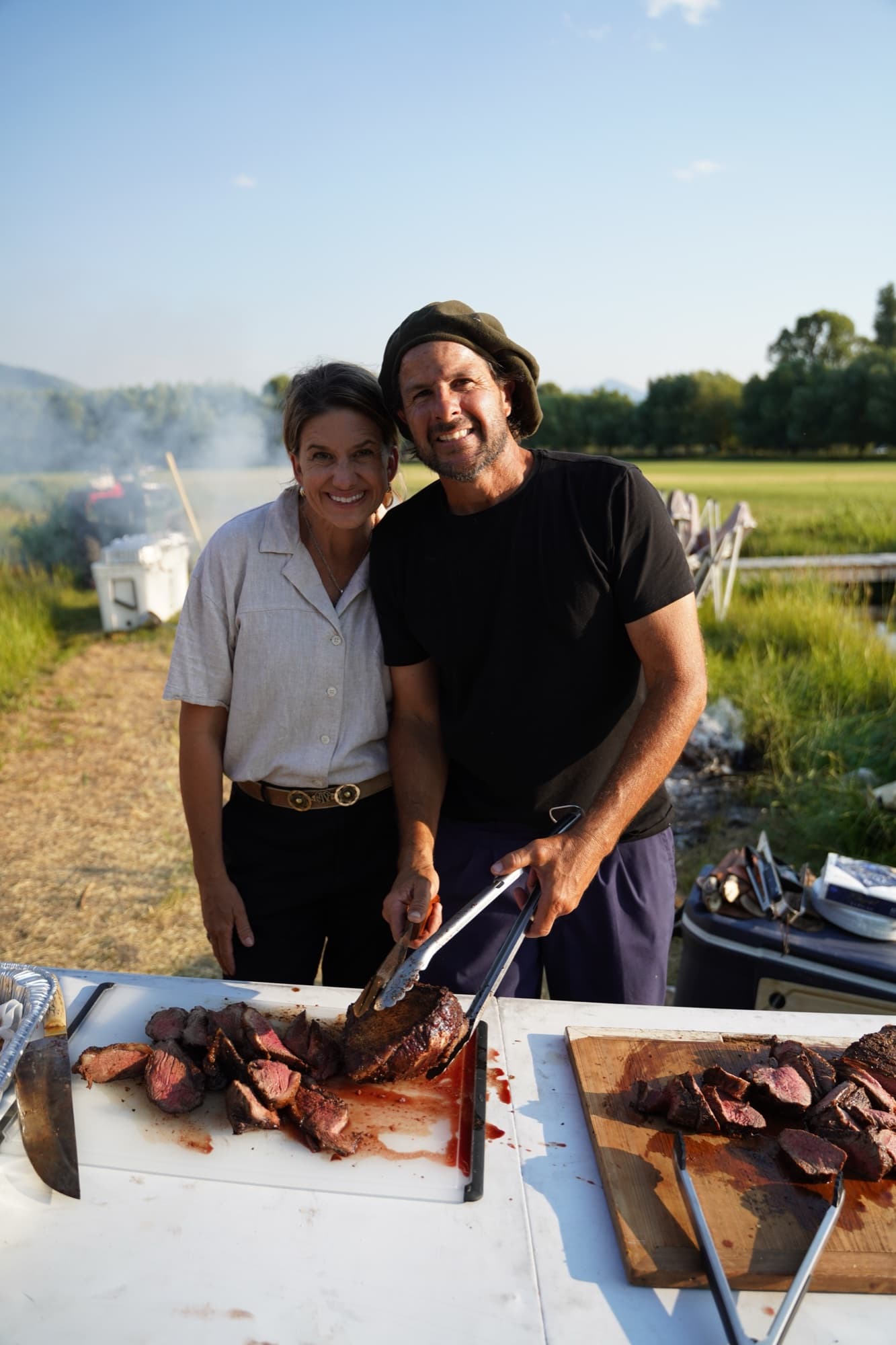 Marcos and Mandi smiling together over a board of freshly carved beef